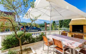 a table and chairs under an umbrella on a patio at Beautiful Apartment In Slano With 2 Bedrooms, Sauna And Wifi in Slano