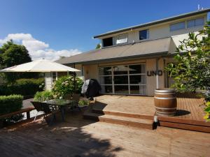 ein Haus mit einer Terrasse mit einem Tisch und einem Sonnenschirm in der Unterkunft Macadamia Retreat - City Central Hygge in Rotorua