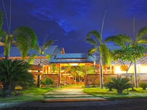 a house with palm trees in front of it at night at Baan Siriporn Resort - โรงแรมบ้านศิริพร รีสอร์ท in Samut Songkhram