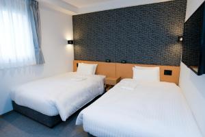um quarto de hotel com duas camas e uma janela em YOU STYLE HOTEL HAKATA em Fukuoka