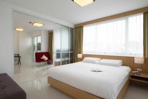a bedroom with a large white bed and a chair at Modern Thai Suites in Phuket