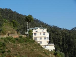 una casa blanca al lado de una colina en Vatsalyam Home Stay, en Shimla