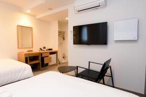 a hotel room with a desk and a tv on the wall at YOU STYLE HOTEL HAKATA in Fukuoka