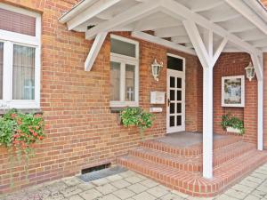 a brick house with a porch with a white roof at Hotel Roseneck in Hagenow