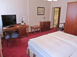 Hotel Roseneck في Hagenow: غرفة فندقية فيها سرير ومكتب وتلفزيون