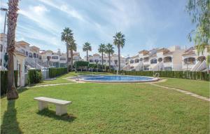 un parc avec un banc, des palmiers et des maisons dans l'établissement Lovely Apartment In Gran Alacant With Kitchen, à Santa Pola