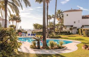 マルベーリャにあるAmazing Apartment In Marbella With Outdoor Swimming Poolの家の前のヤシの木があるプール