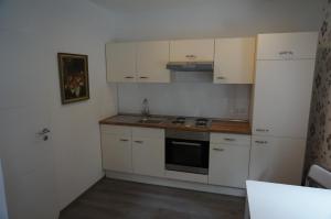 トルガウにあるPension am Seeの白いキャビネット、シンク、冷蔵庫付きのキッチンが備わります。