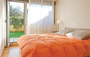 Beautiful Apartment In Llanes With Kitchen في يانس: سرير برتقالي في غرفة مع نافذة كبيرة