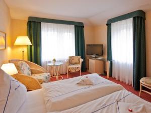 ein Hotelzimmer mit einem Bett und Stühlen sowie einem TV in der Unterkunft Park-Hotel in Timmendorfer Strand