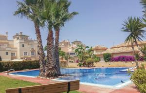 Nice Home In Orihuela Costa With Outdoor Swimming Pool في أوريويلا كوستا: مسبح فيه نخل قدام بيت