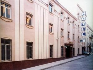 ein Gebäude auf einer Straße mit einem Auto direkt daneben. in der Unterkunft Hotel Victoria in Linares