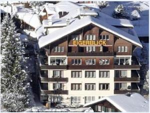 a large building with a sign on it in the snow at Hotel Eigerblick in Grindelwald