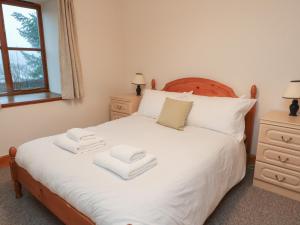 Un dormitorio con una cama blanca con toallas. en Bruce en Pitlochry