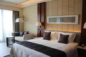 三亜市にあるクラウン プラザ サンヤ シティ センターの大きなベッドとソファが備わるホテルルームです。