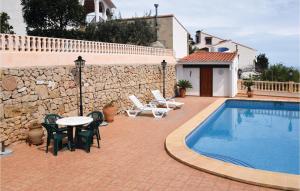 eine Terrasse mit einem Tisch, Stühlen und einem Pool in der Unterkunft 3 Bedroom Beautiful Home In Oliva in Oliva