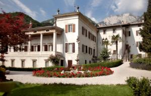 a large white building with flowers in a garden at Villa Sizzo Relais B&B in Trento