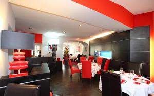 a dining room with tables and red chairs at Auberge bretonne in Châteaubriant