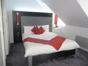 Un dormitorio con una cama grande con almohadas rojas. en Auberge bretonne, en Châteaubriant