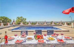 a table with food and wine glasses and a swimming pool at Awesome Home In Almodvar Del Ro With 5 Bedrooms, Wifi And Outdoor Swimming Pool in Almodóvar del Río