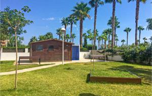 a park with two benches and a building with palm trees at Gorgeous Apartment In Oropesa Del Mar in Oropesa del Mar