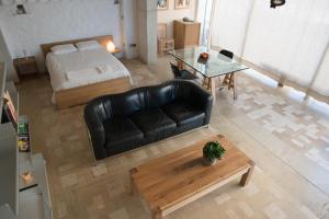 a living room with a bed and a black leather couch at City Centre Studios in Limassol