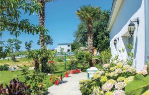 a garden with flowers and palm trees next to a building at Awesome Home In Bénodet With Wifi in Bénodet
