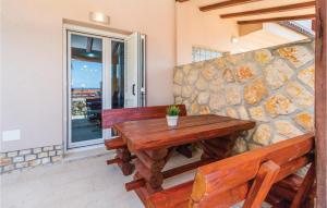 a wooden table with two benches and a stone wall at Stunning Apartment In Dramalj With Wifi in Dramalj
