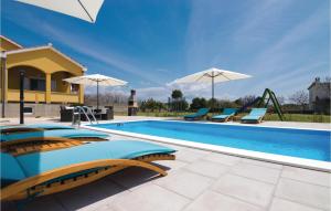 a swimming pool with chairs and a slide at 3 Bedroom Lovely Home In Vrsi in Vrsi