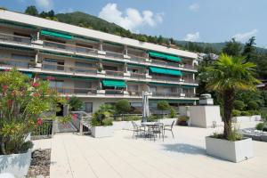 un bâtiment avec des tables et des chaises dans une cour dans l'établissement Collina d'Oro Orselina Locarno, à Locarno