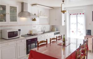 a kitchen with white cabinets and a table and a microwave at Amazing Home In Plonevez Porzay With 2 Bedrooms in Plonévez-Porzay