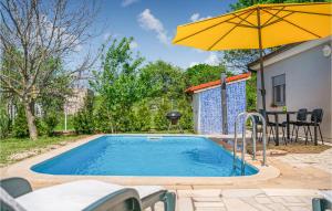 a pool with an umbrella and a table and chairs at Stunning Home In Loborika With 2 Bedrooms, Private Swimming Pool And Outdoor Swimming Pool in Loborika
