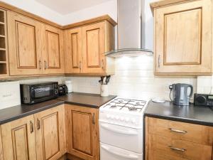 a kitchen with wooden cabinets and a white stove top oven at The Nook 285B in Colwyn Bay