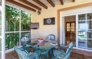 una mesa de cristal y sillas en un porche con TV en Lovely Home In Benajarafe With House Sea View, en Benajarafe