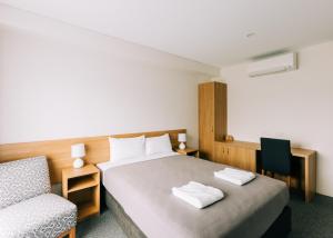 a hotel room with a bed and a chair at Voyager Motel in Wallgrove