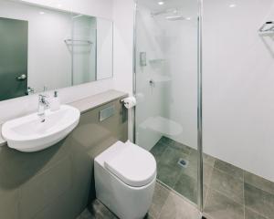 a bathroom with a toilet and a sink and a shower at Voyager Motel in Wallgrove