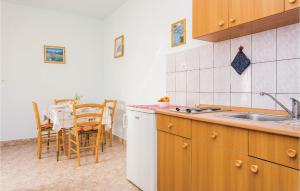 a kitchen with a sink and a table with chairs at Awesome Apartment In Kornic With House Sea View in Kornić