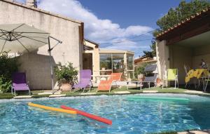 アヴィニョンにあるCozy Home In Avignon With Wifiのカラフルな椅子とパラソル付きのスイミングプール