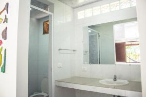 a white bathroom with a sink and a mirror at Isla Grande Eco-Hostal in Isla Grande