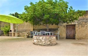 einen Tisch und Stühle unter einem Baum neben einem Gebäude in der Unterkunft Gorgeous Home In Aramon With Wifi in Aramon