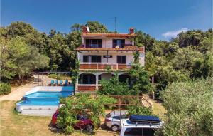 a house with a pool and cars parked in front of it at Awesome Apartment In Supetarska Draga With 1 Bedrooms, Wifi And Outdoor Swimming Pool in Supetarska Draga