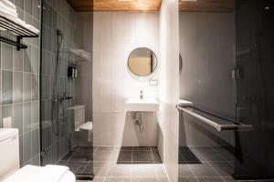 ein Bad mit einem Waschbecken, einer Dusche und einem Spiegel in der Unterkunft Traveller-Inn Day Moon Hotel in Taitung