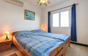 a bedroom with a bed with a blue comforter and a window at Awesome Home In Roquebrune-Sur-Argens in Saint-Peïre-sur-Mer
