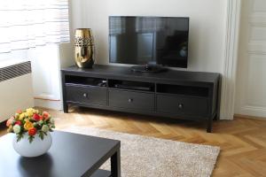 ein schwarzes Unterhaltungszentrum mit einem TV im Wohnzimmer in der Unterkunft Royal Prague Apartment Celakovskeho Sady in Prag