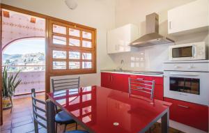 a kitchen with red cabinets and a red table and chairs at 2 Bedroom Cozy Home In Faro De Cullera in Faro de Cullera