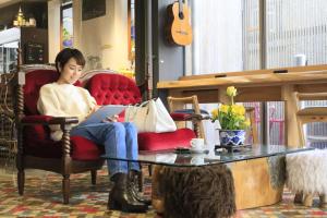 a woman sitting in a red chair with a laptop at Andon Ryokan in Tokyo