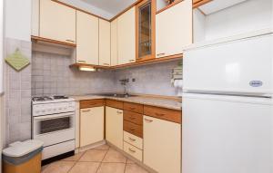 a kitchen with white cabinets and a white refrigerator at 2 Bedroom Nice Apartment In Potocnica in Potocnica