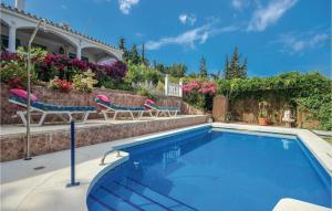 a swimming pool with two chairs and a house at Stunning Apartment In Urb El Chaparral With 1 Bedrooms, Outdoor Swimming Pool And Swimming Pool in Mijas Costa