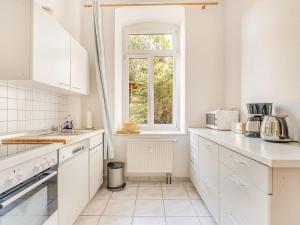 uma cozinha com armários brancos e uma janela em Apartment with large communal terrace em Wünschendorf