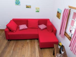 ein rotes Sofa mit zwei Kissen im Wohnzimmer in der Unterkunft Apartment with garden near Monschau in Schleiden